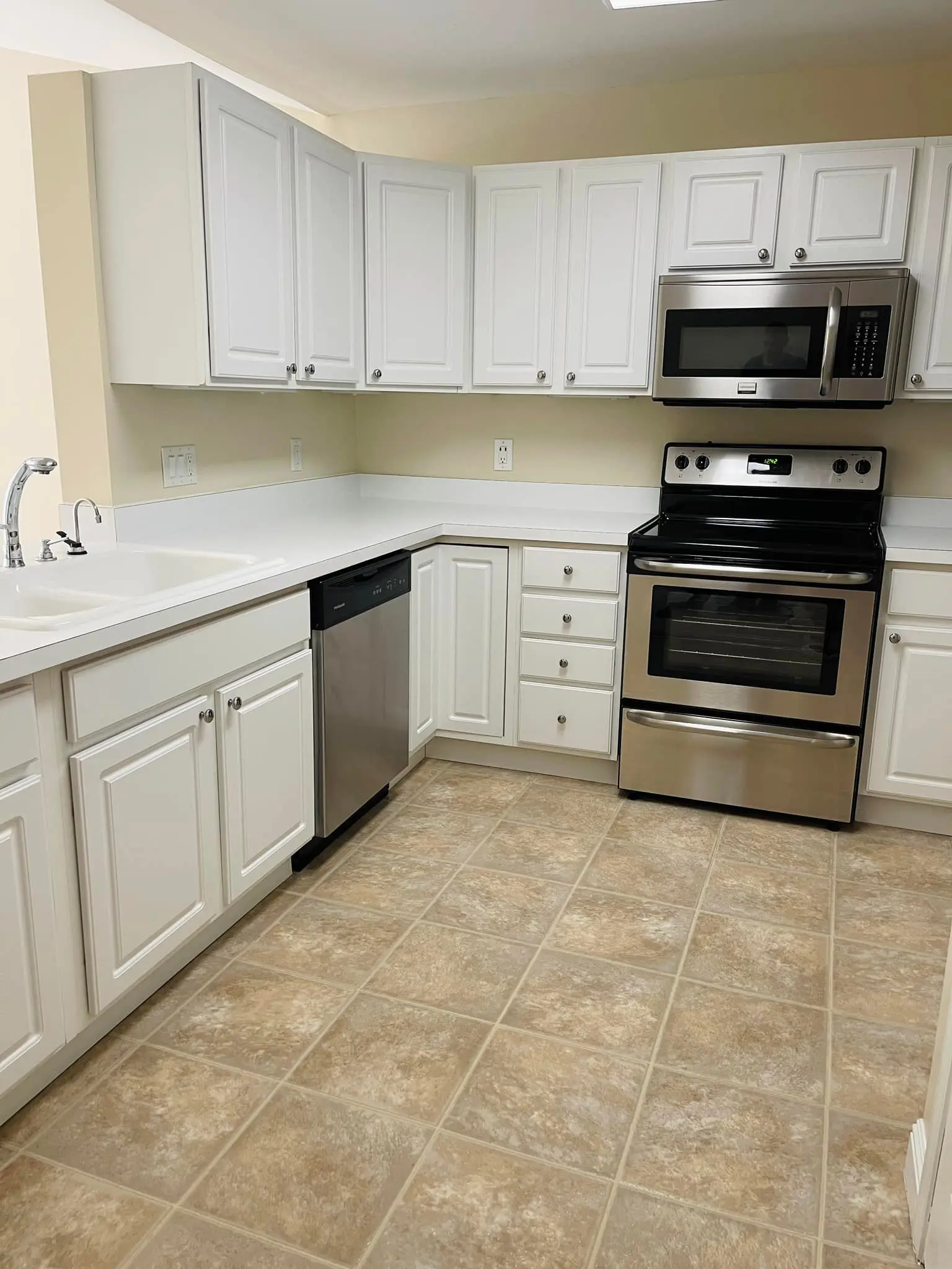 Modern kitchen with white cabinets and stainless steel appliances.