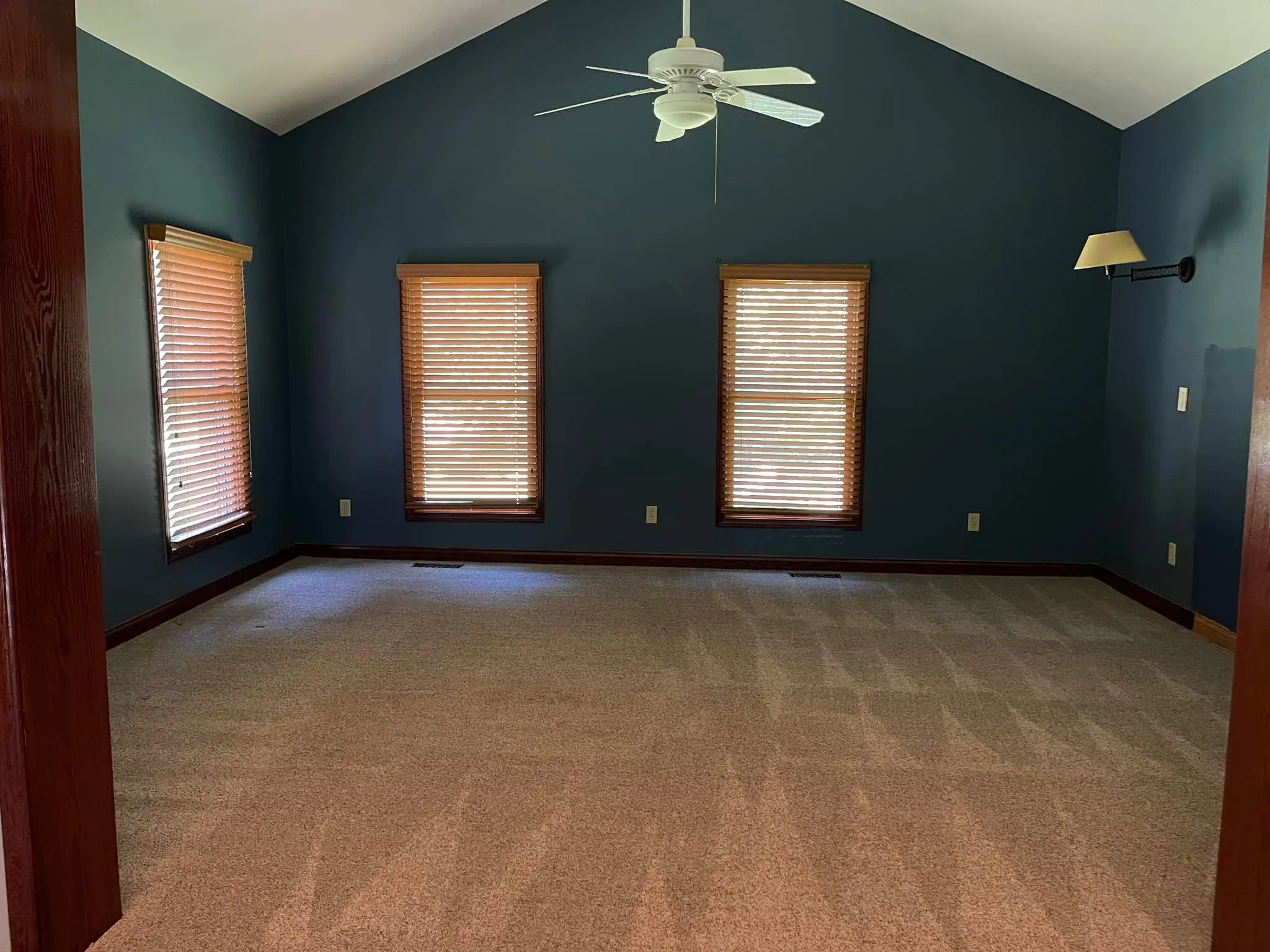 Empty room with dark blue walls and beige carpet.