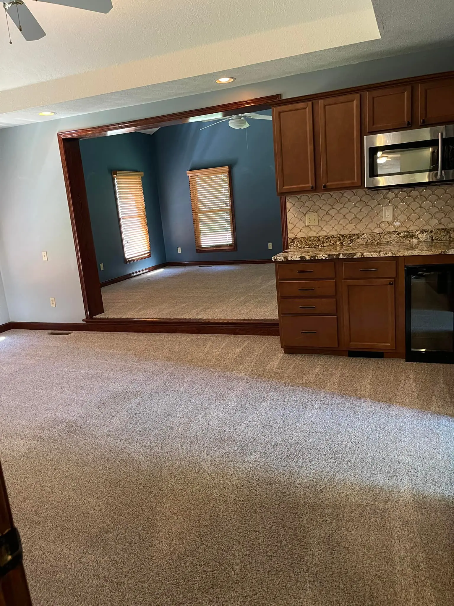 Empty kitchen and living area with carpet and tile flooring.