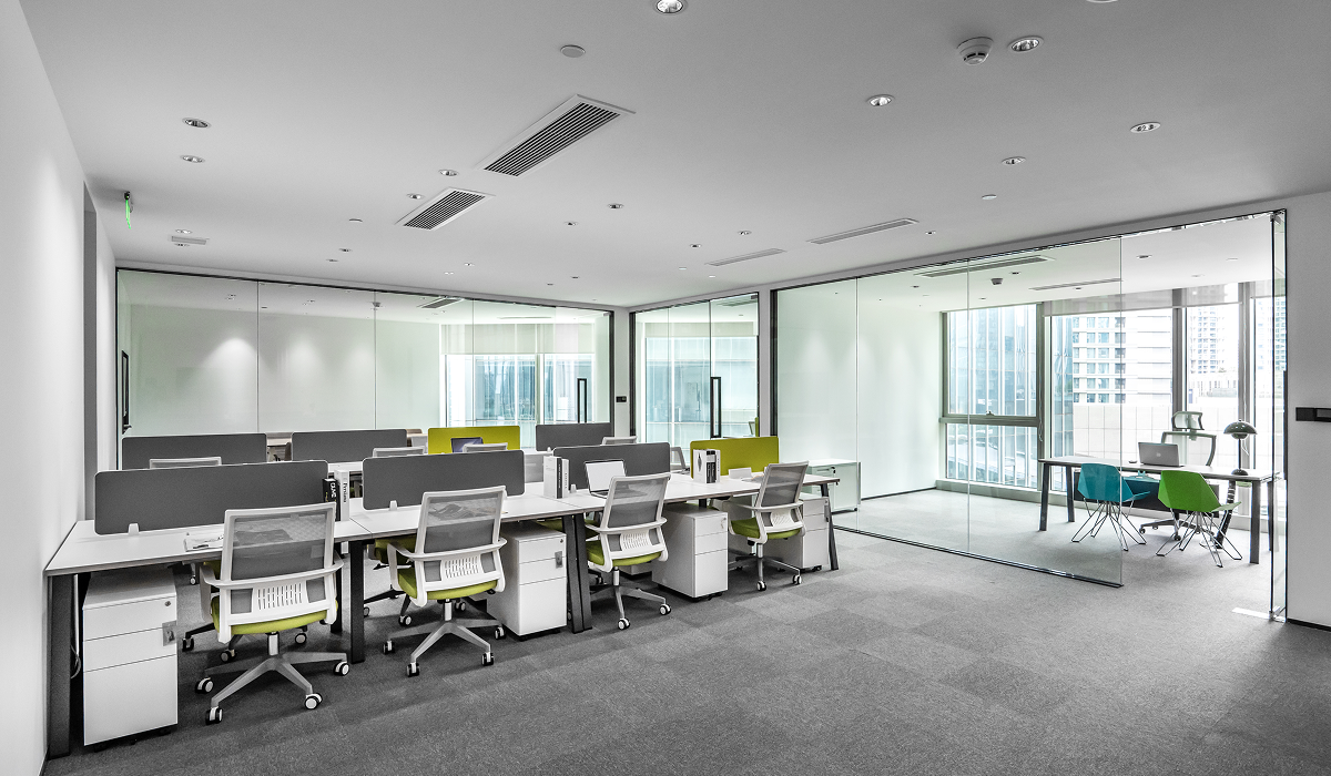 Modern office space with desks, chairs, and glass partitions.