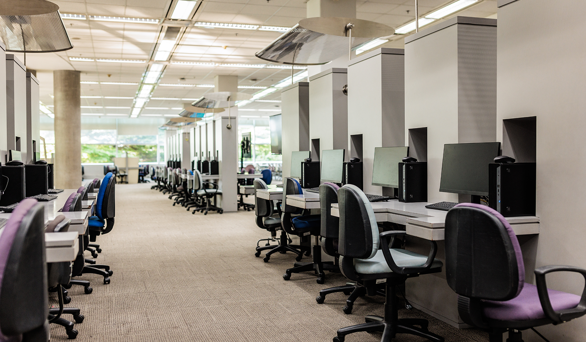 Empty modern office with rows of desks and computers.