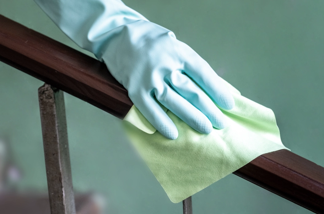Cleaning wooden banister with gloves