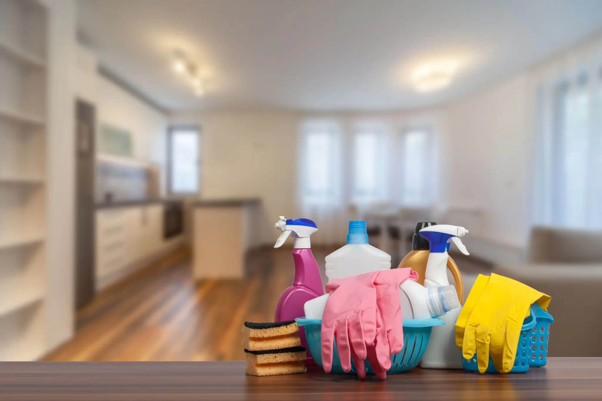 Cleaning supplies and gloves on a table in a bright home kitchen.